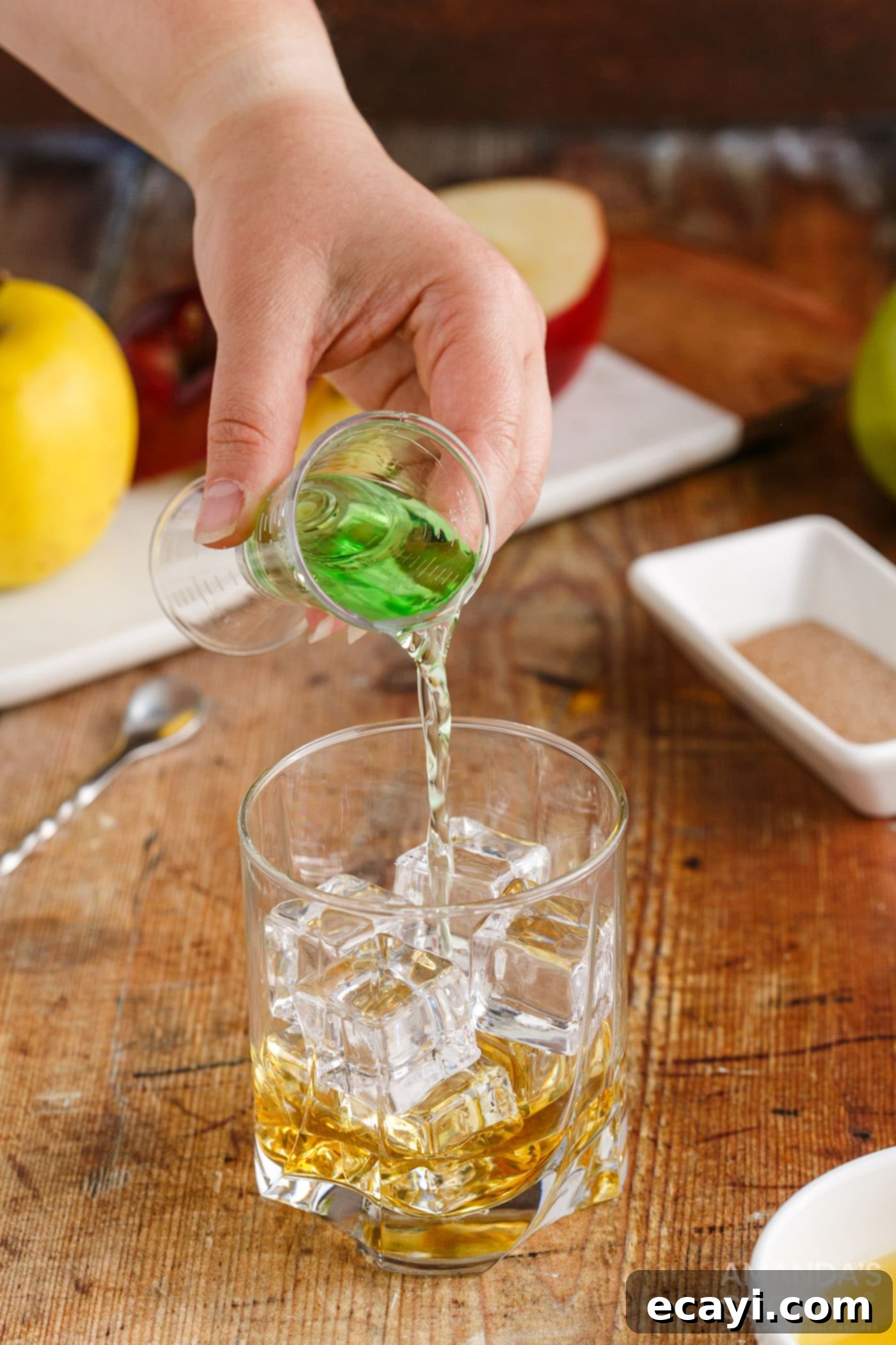 Harvest Spice Apple Elixir 6 pouring apple pucker into a rock glass with ice