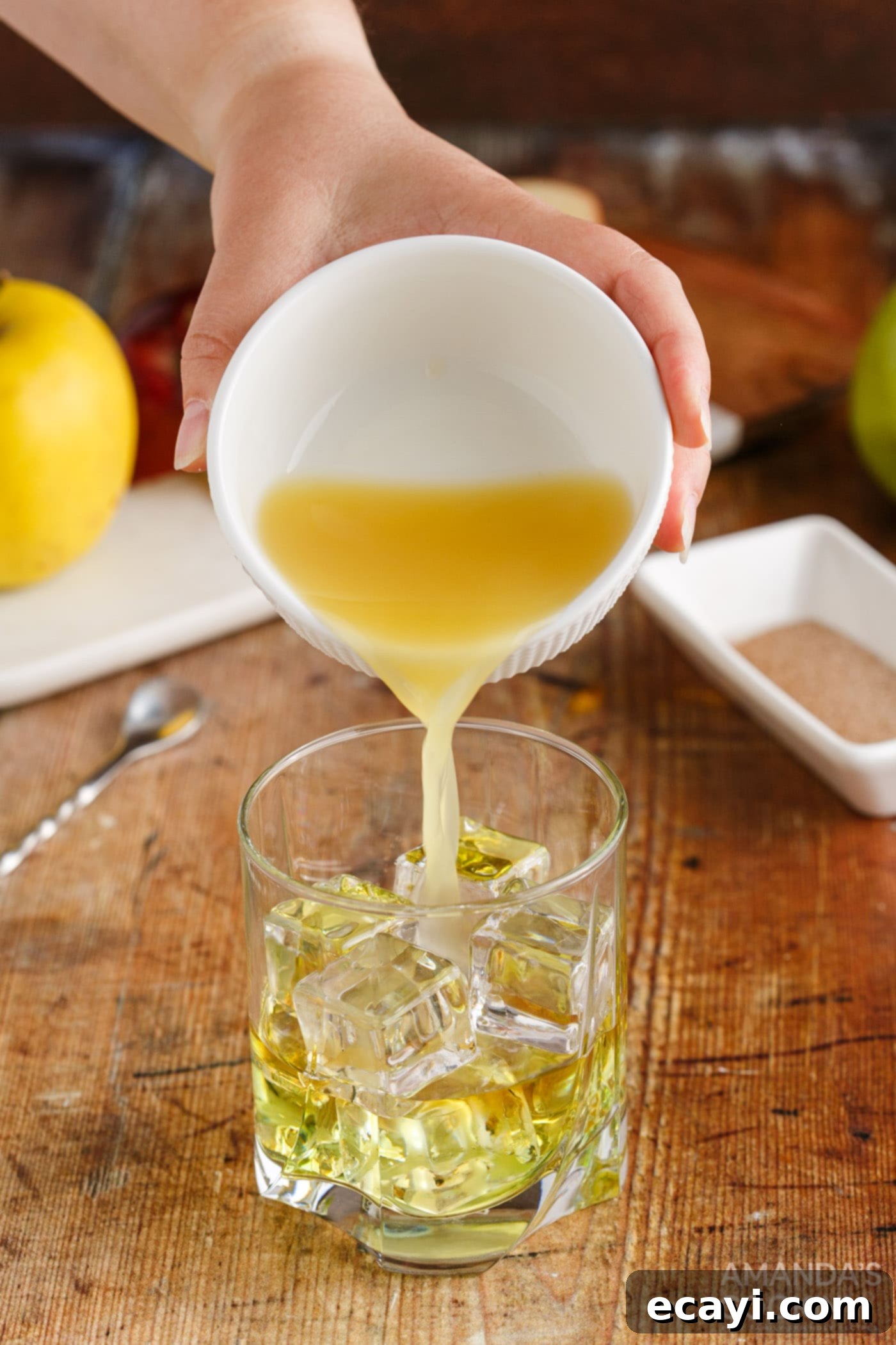 Harvest Spice Apple Elixir 7 pouring pineapple juice into a rock glass with other cocktail ingredients