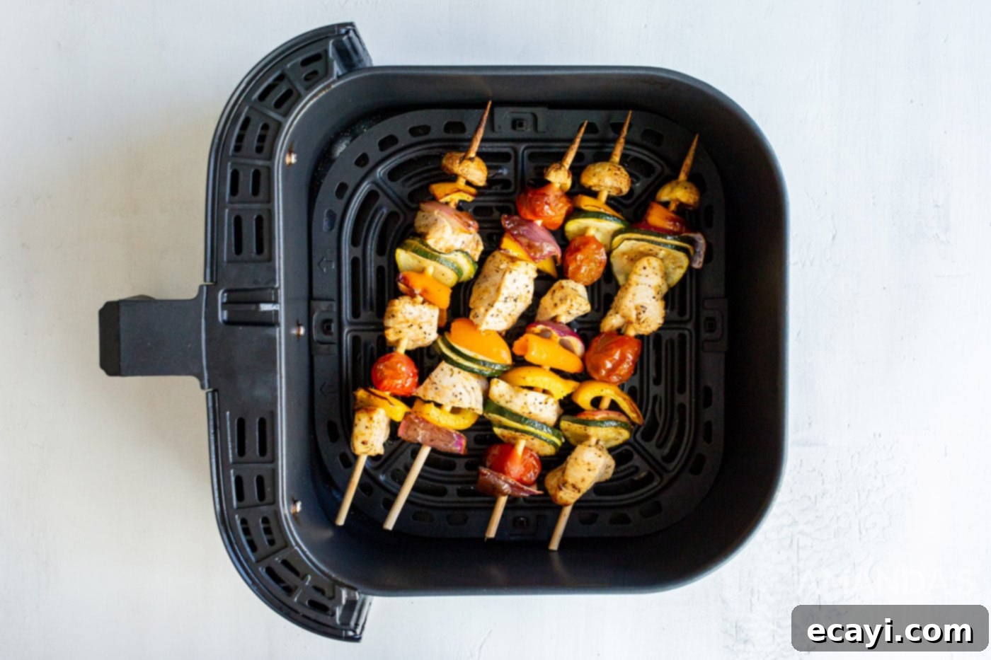 Effortless Air Fryer Chicken Kabobs 8 Cooked chicken kabobs resting in the air fryer basket after cooking