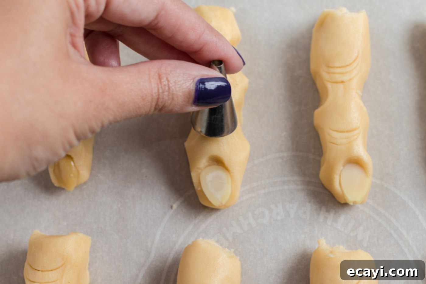 Wicked Fingers 12 A piping tip skillfully making indents in cookie dough, adding grotesque details to the Witch Finger Cookies