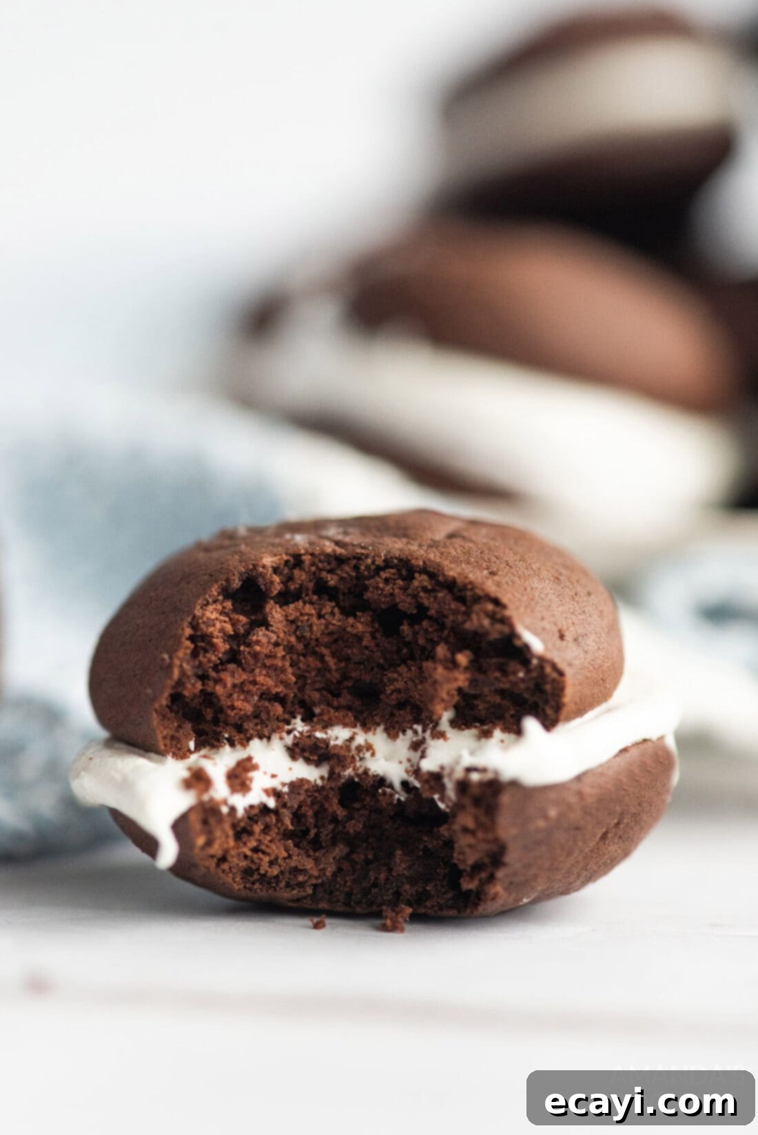 Velvety Chocolate Whoopie Indulgence 13 A half-eaten Chocolate Whoopie Pie, revealing the soft chocolate cake and creamy marshmallow filling within.