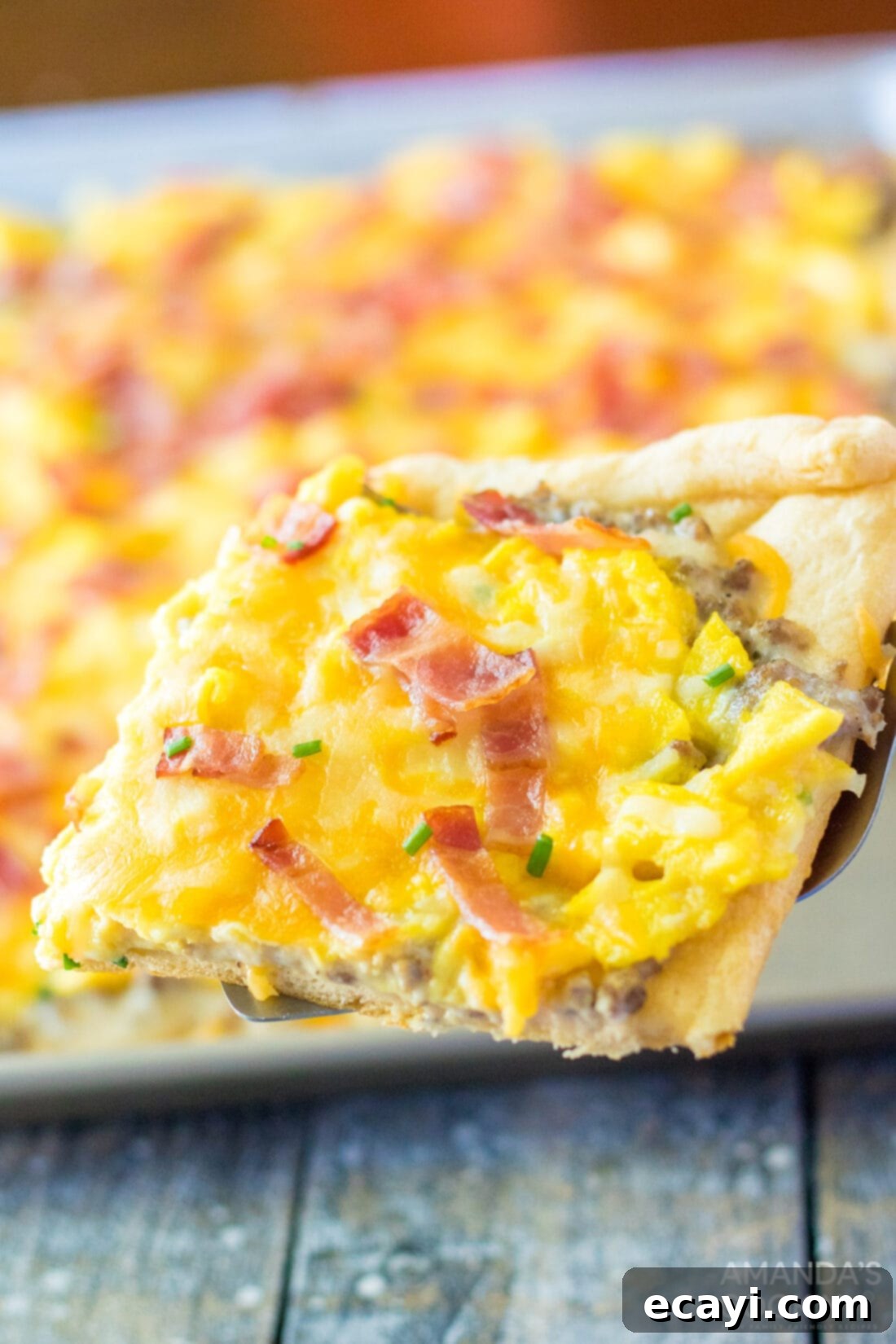 One-Pan Breakfast Pizza 3 spatula lifting a piece of Sheet Pan Breakfast Pizza