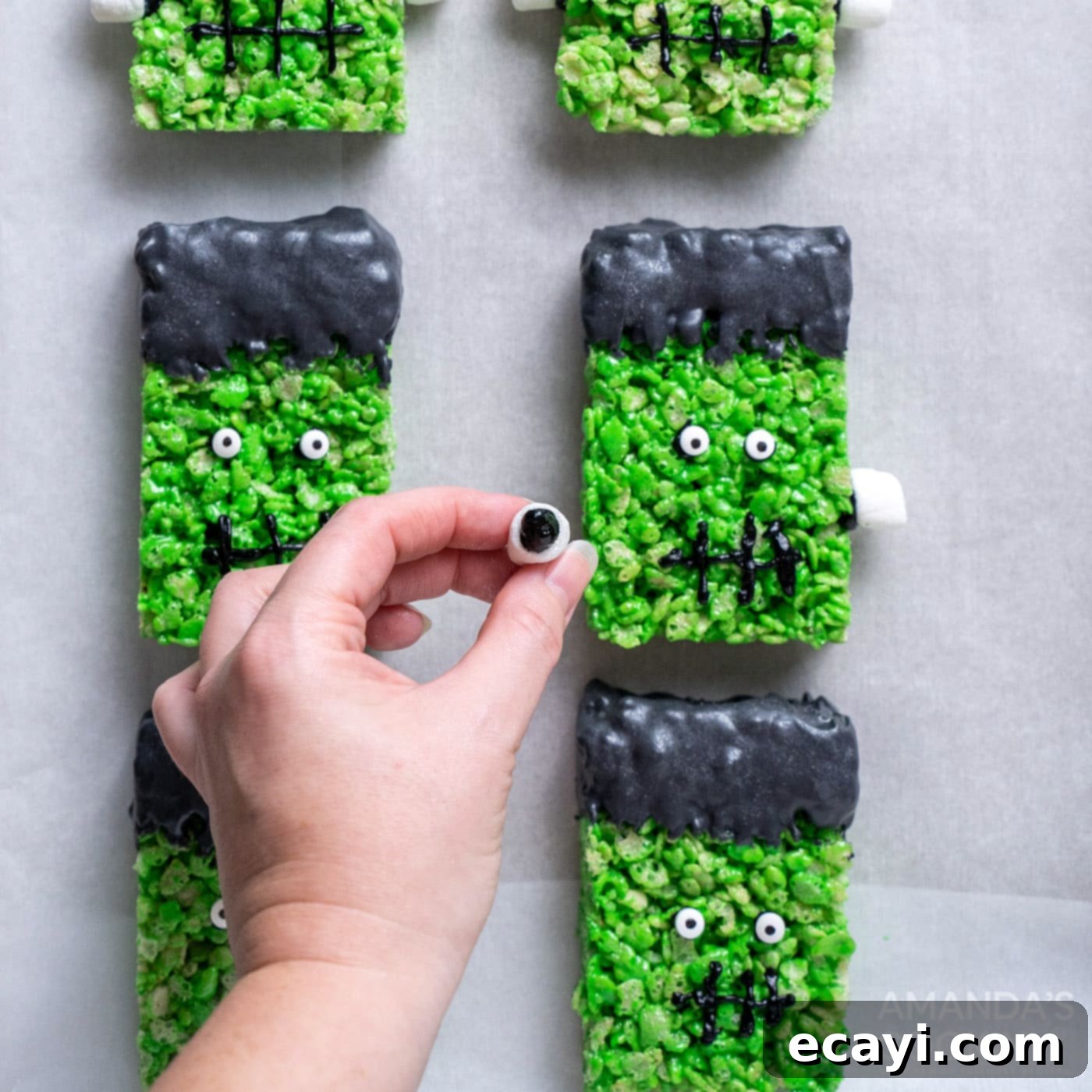 Franken-Crispy Treats 15 hand attaching mini marshmallows to frankenstein rice krispie treats
