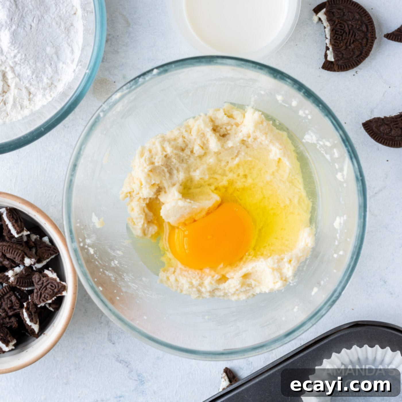 Ultimate Oreo Cupcakes 6 egg being added to the creamy cupcake batter mixture