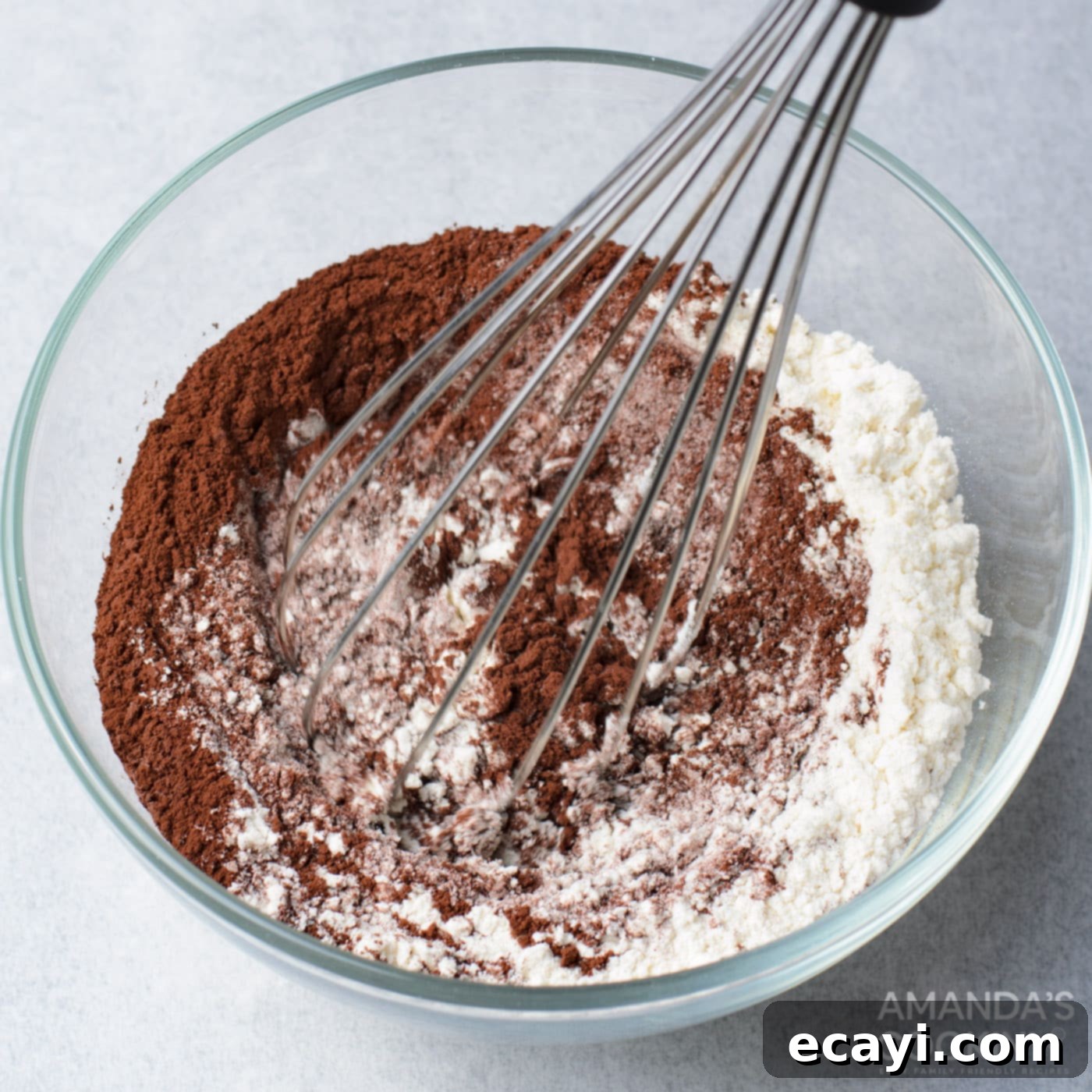 Decadent Oreo Cheesecake Brownies 6 A close-up shot of a whisk combining flour, cocoa powder, and salt in a bowl, demonstrating the preparation of dry ingredients for the brownie base.