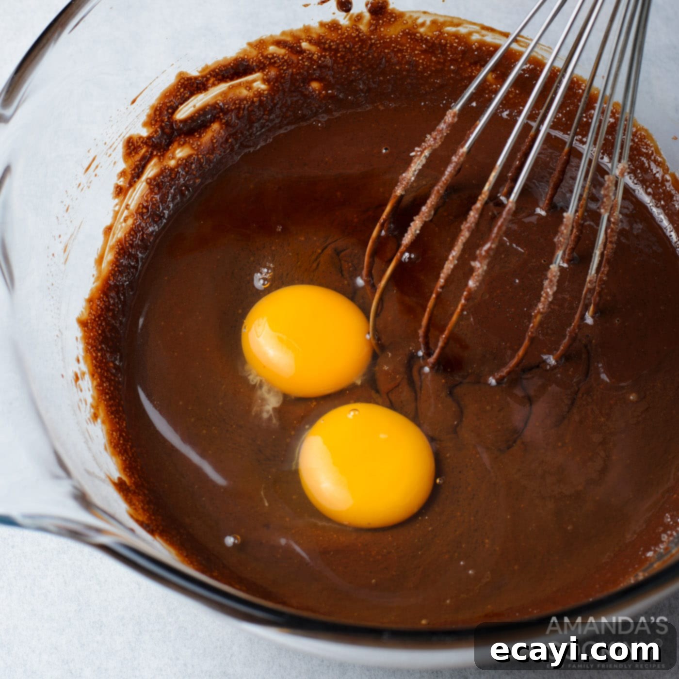 Decadent Oreo Cheesecake Brownies 7 Brownie batter in a bowl, showing eggs just whisked in, creating a rich, smooth consistency before the dry ingredients are added.