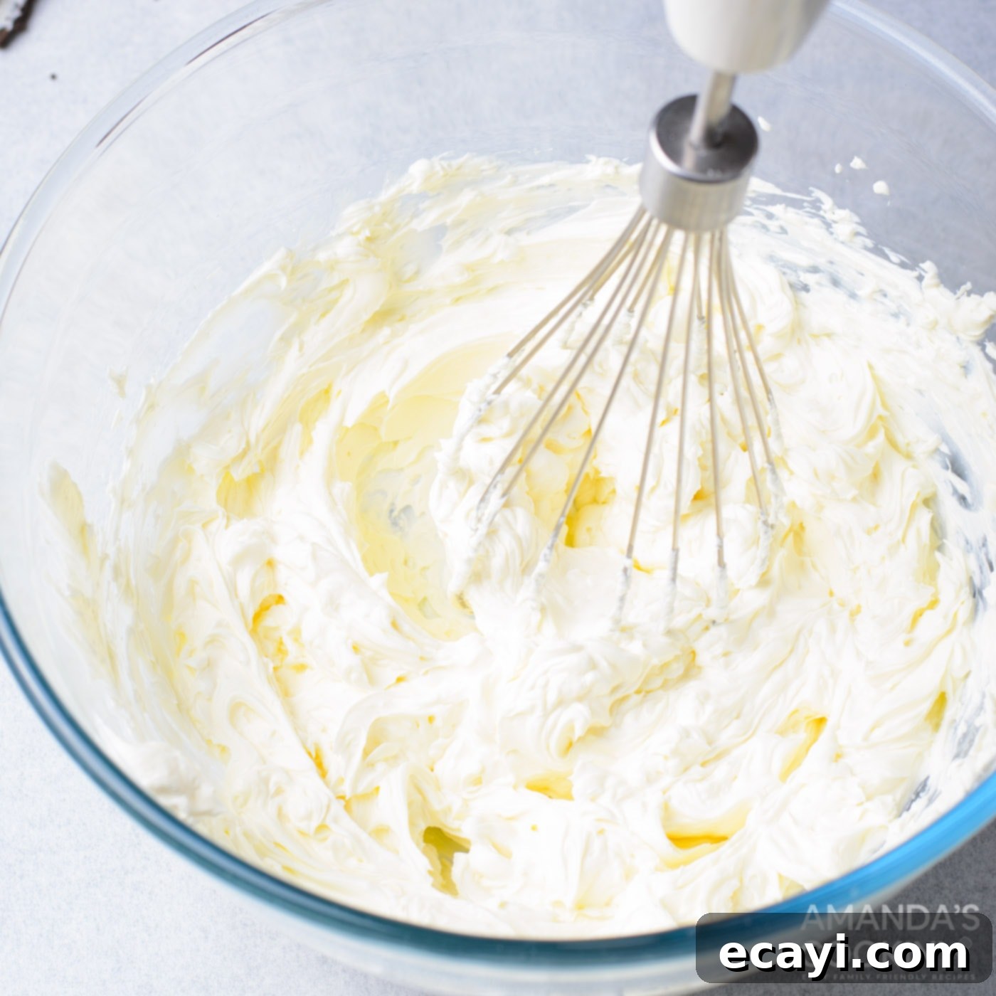 Decadent Oreo Cheesecake Brownies 9 A hand mixer blending softened cream cheese in a bowl, creating a smooth and fluffy base for the creamy cheesecake layer.