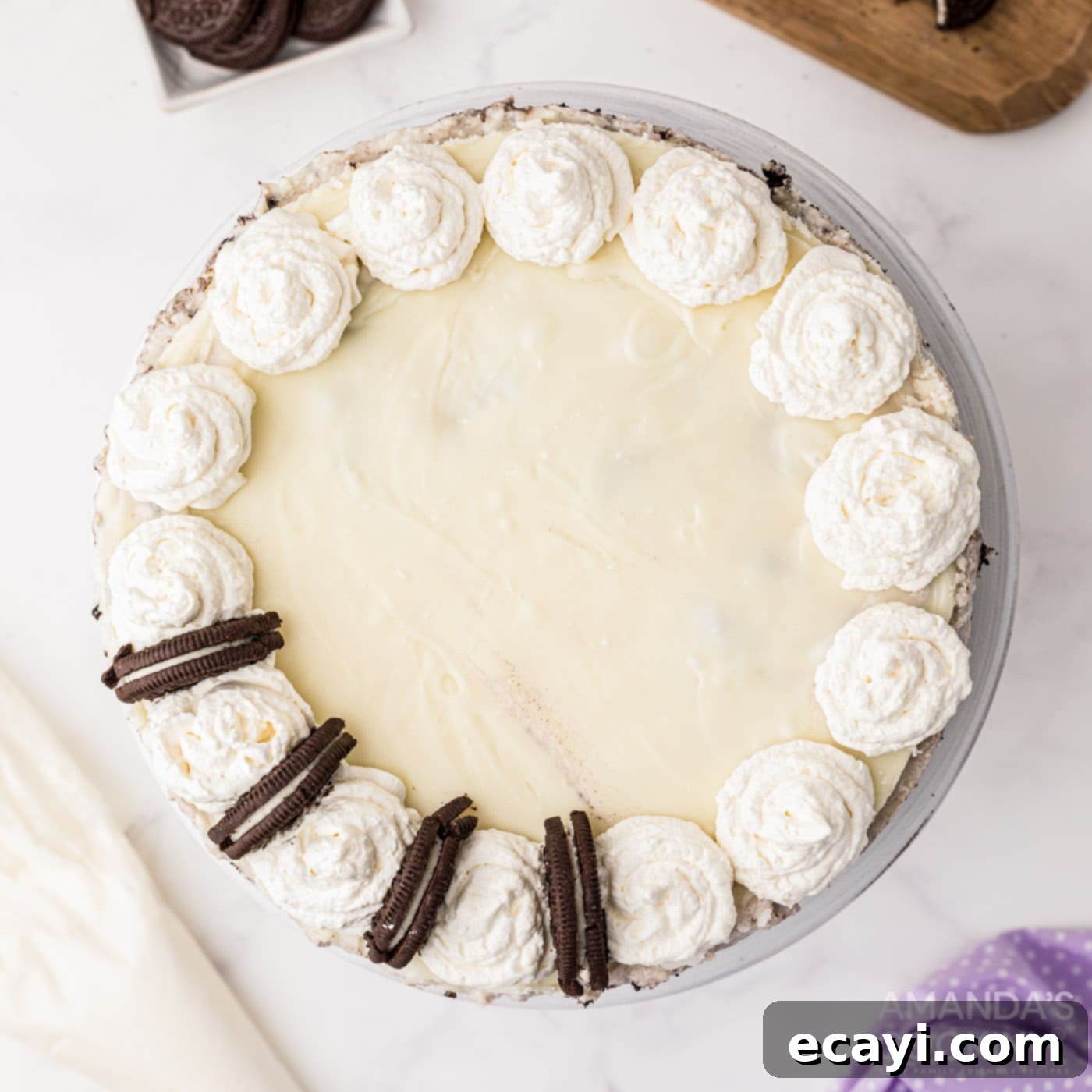 Decadent Oreo Cheesecake 12 Decorated Oreo Cheesecake with whipped cream swirls and halved Oreo cookies placed elegantly between them on top of the ganache.