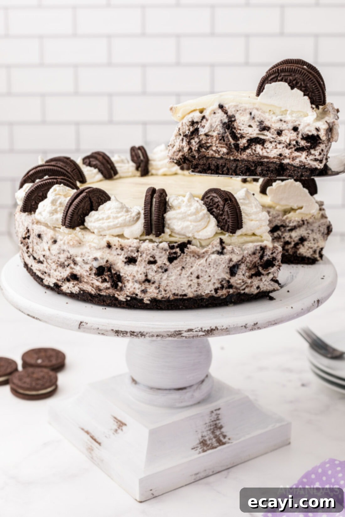 Decadent Oreo Cheesecake 13 A hand gently removing a slice of the magnificent Oreo Cheesecake from the main cake, showcasing its layers and rich texture.