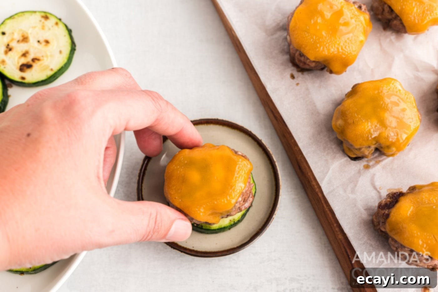 Mini Zucchini Bites 12 hand placing a cheesy burger patty on a zucchini round