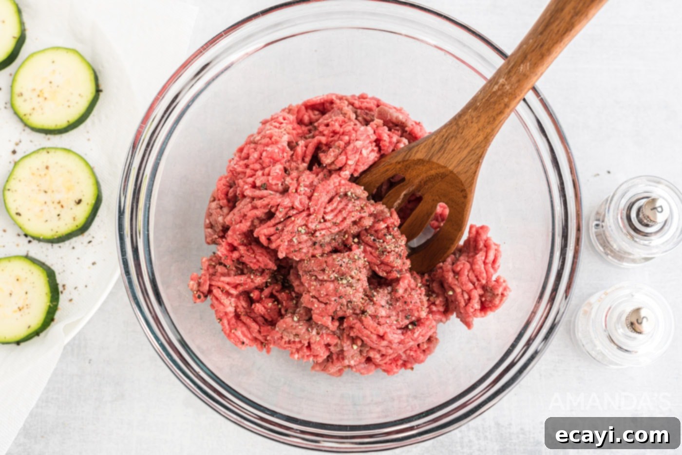 Mini Zucchini Bites 6 mixing spoon in a bowl of ground beef with salt and pepper