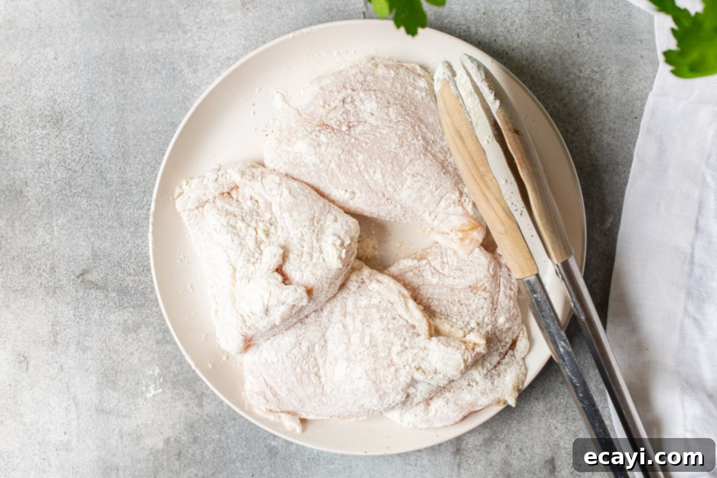 Lemon Caper Chicken 5 Flour-coated chicken breasts seasoned with salt and pepper, ready for pan-frying.