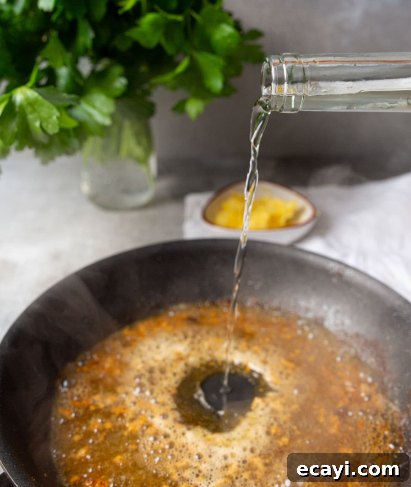 Lemon Caper Chicken 7 Pouring white wine into a hot skillet with butter and garlic.