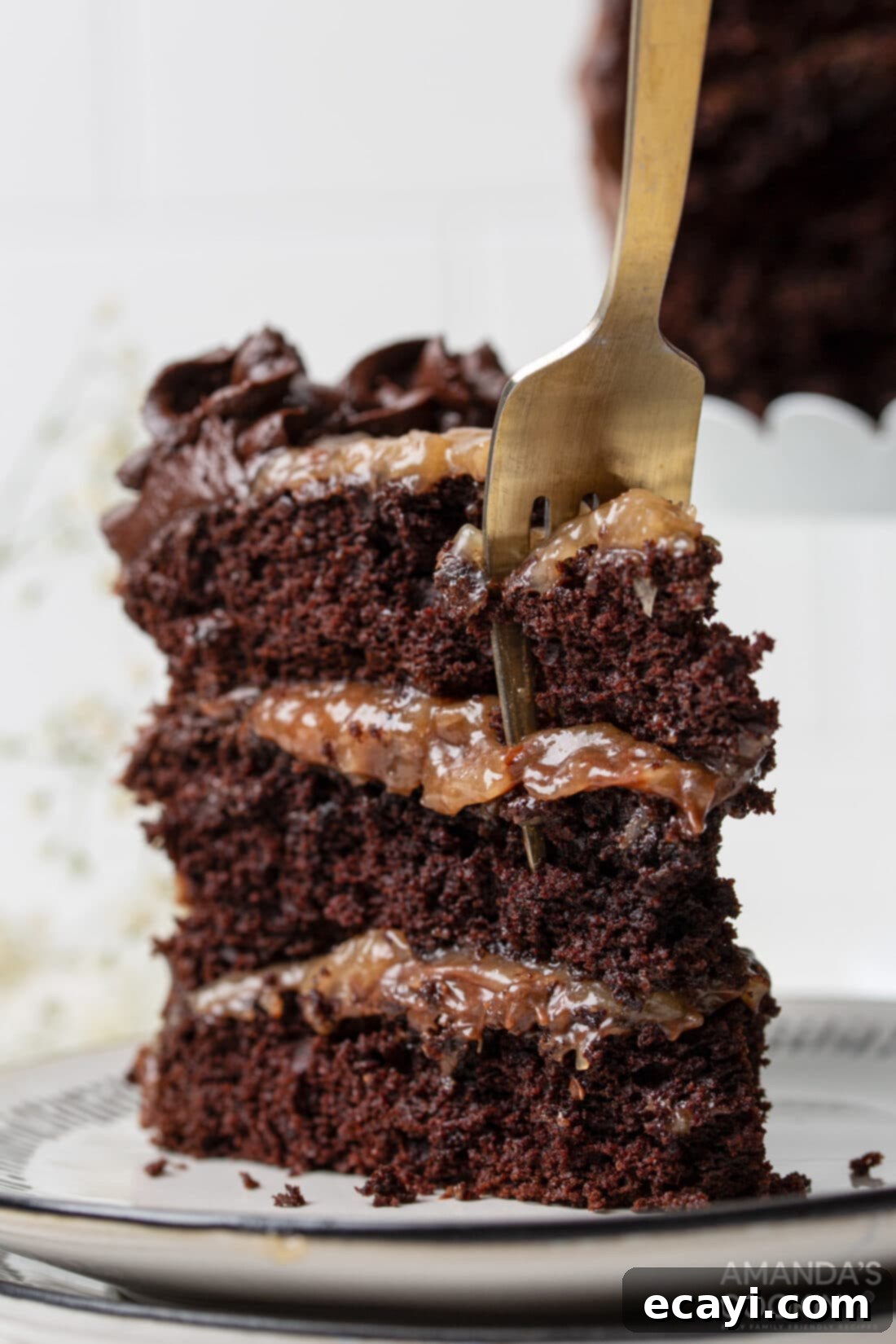 Decadent Coconut Pecan Chocolate Cake 3 A fork taking a bite from a slice of German Chocolate Cake, revealing moist layers and filling