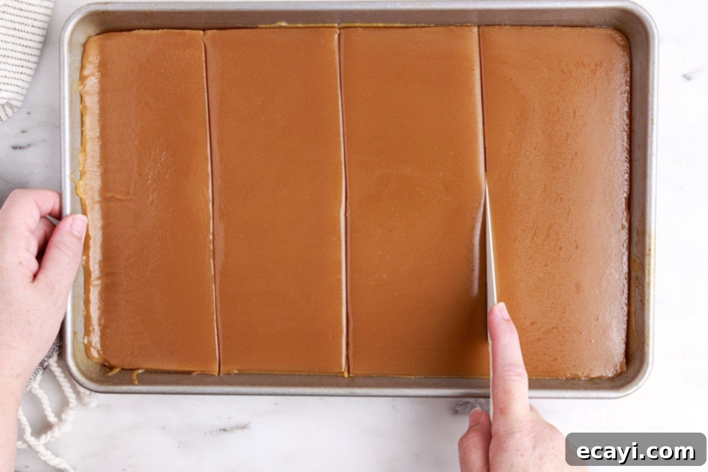 Microwave's Golden Delight 7 Slicing cooled microwave caramels on a parchment-lined sheet pan