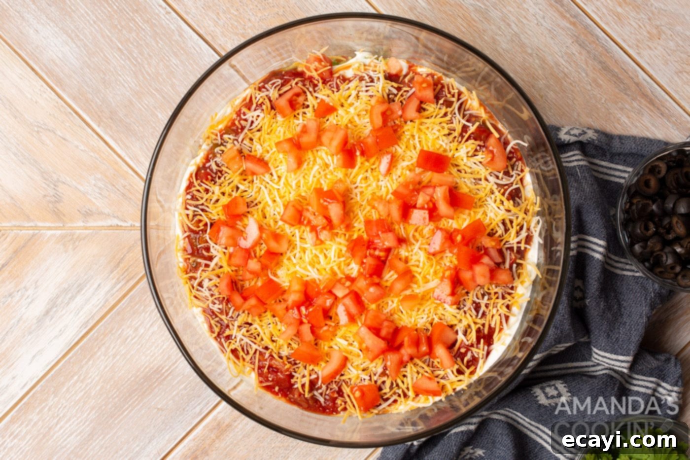 Ultimate Seven Layer Taco Dip 8 tomatoes on top of cheese in a bowl