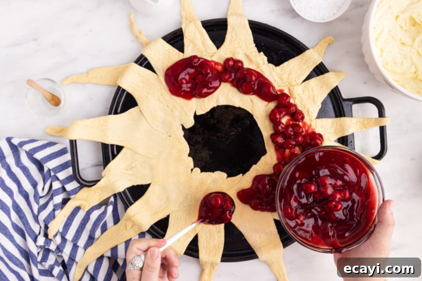 Artisan Danish Wreath 6 Cherry pie filling being spooned onto the crescent roll ring to create the base layer of fruit.