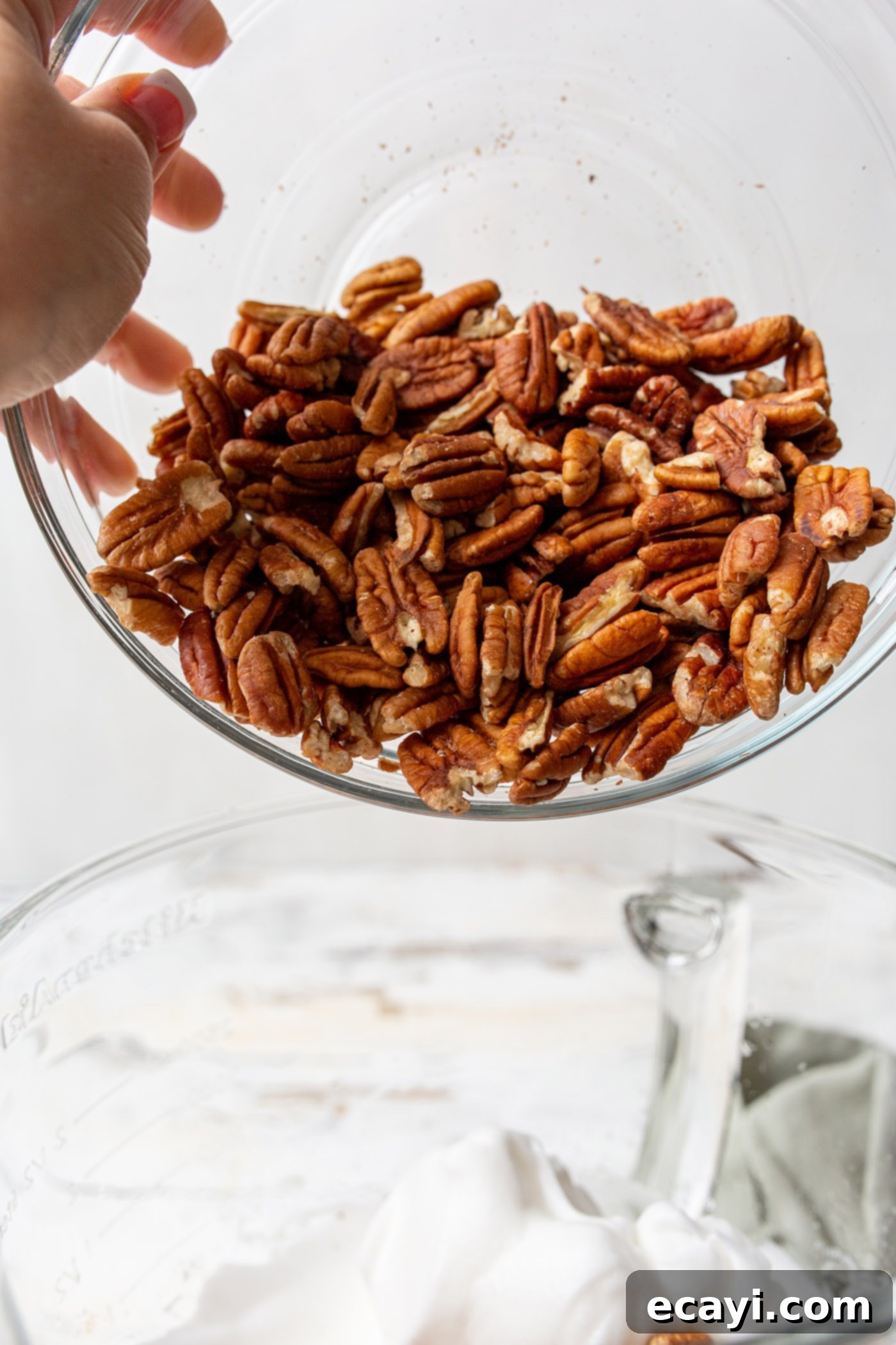 Sweet Pecan Delights 7 Pouring a bowl of pecan halves into the whipped egg white mixture