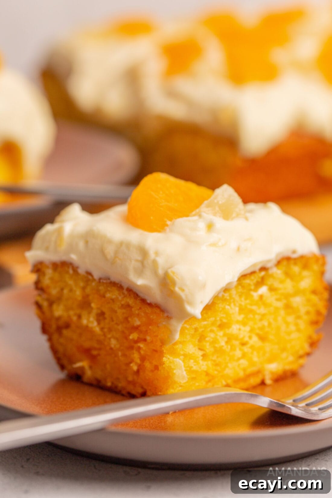 Sunshine Pineapple Orange Cake 2 A vibrant slice of Orange Pineapple Cake topped with fluffy pineapple frosting and mandarin segments