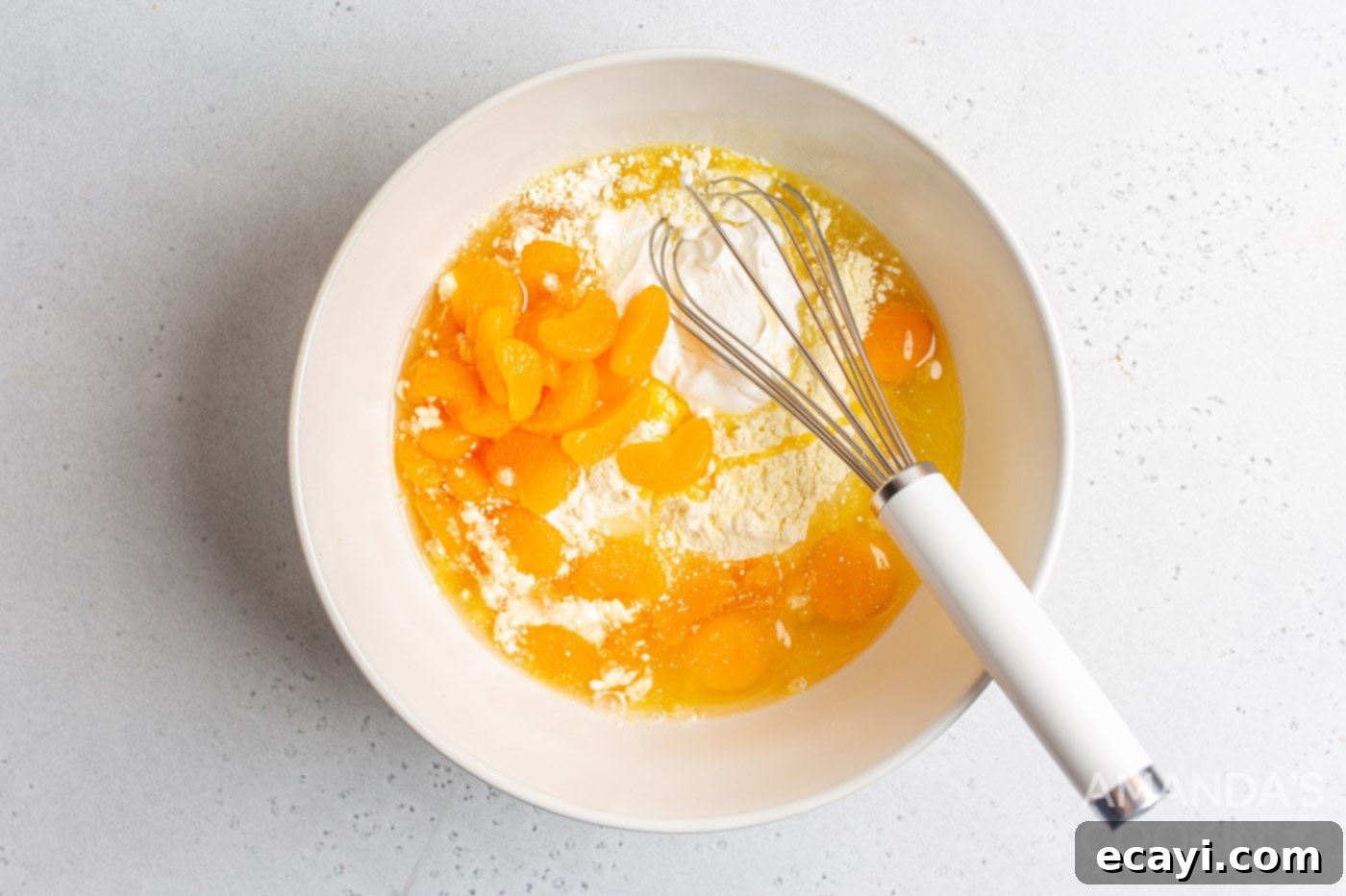 Sunshine Pineapple Orange Cake 5 Yellow cake mix, vegetable oil, sour cream, eggs, and mandarin oranges in a mixing bowl being combined