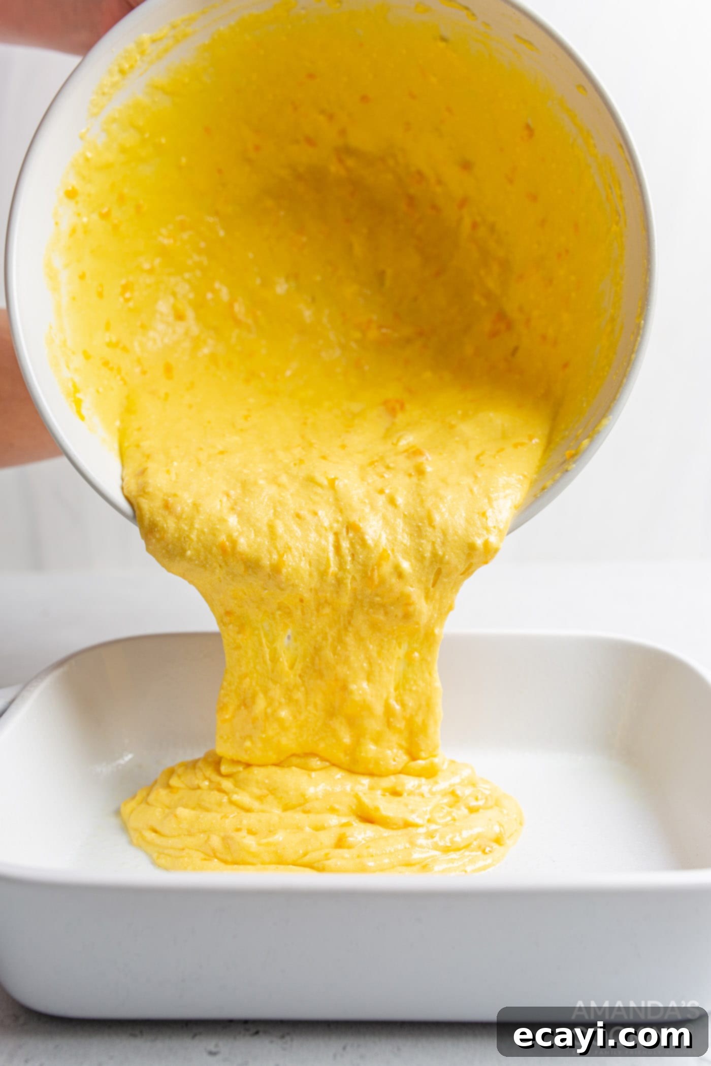 Sunshine Pineapple Orange Cake 6 Pouring orange pineapple cake batter into a greased 9x13 casserole dish