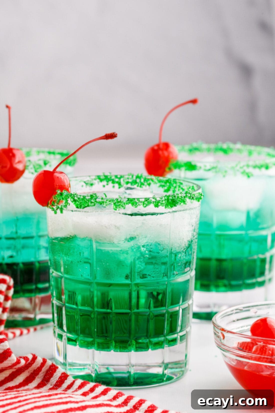 Grinch's Emerald Elixir 2 Vibrant green Grinch Cocktail with a sugared rim and cherry garnish, perfect for holiday celebrations.