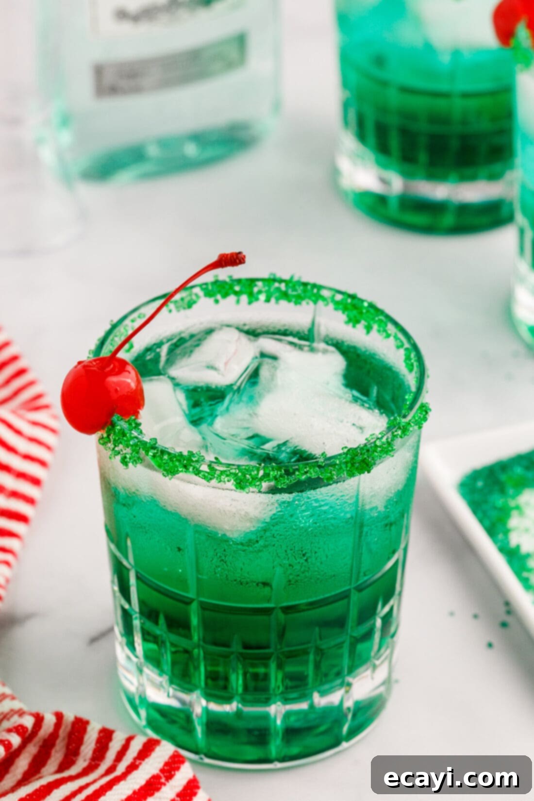 Grinch's Emerald Elixir 3 Close-up of a green Grinch cocktail garnished with a cherry, ready to be enjoyed.
