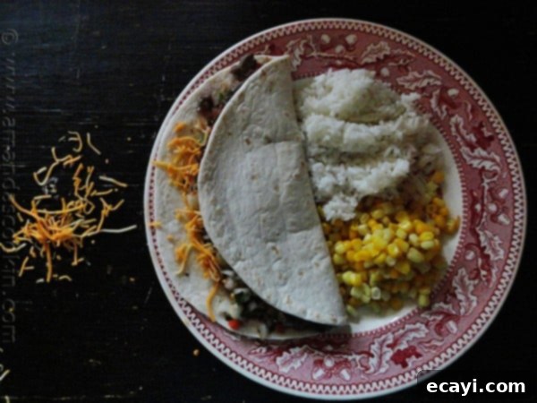 Flavorful Steak Soft Tacos with Sides An overhead photo of two vibrant flank steak soft tacos on a plate with corn and rice on the side, highlighting a complete meal.