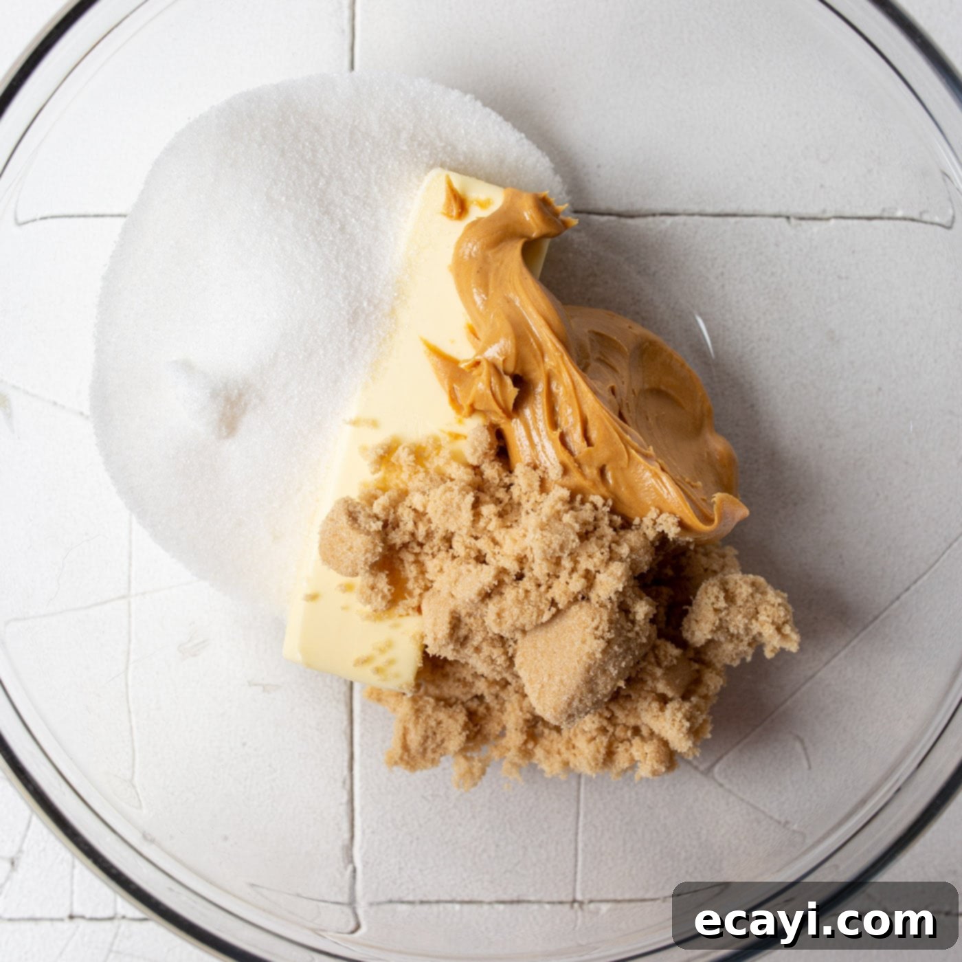 Sweet Christmas Kisses 5 peanut butter, brown sugar, and granulated sugar being creamed together in a mixing bowl with a hand mixer