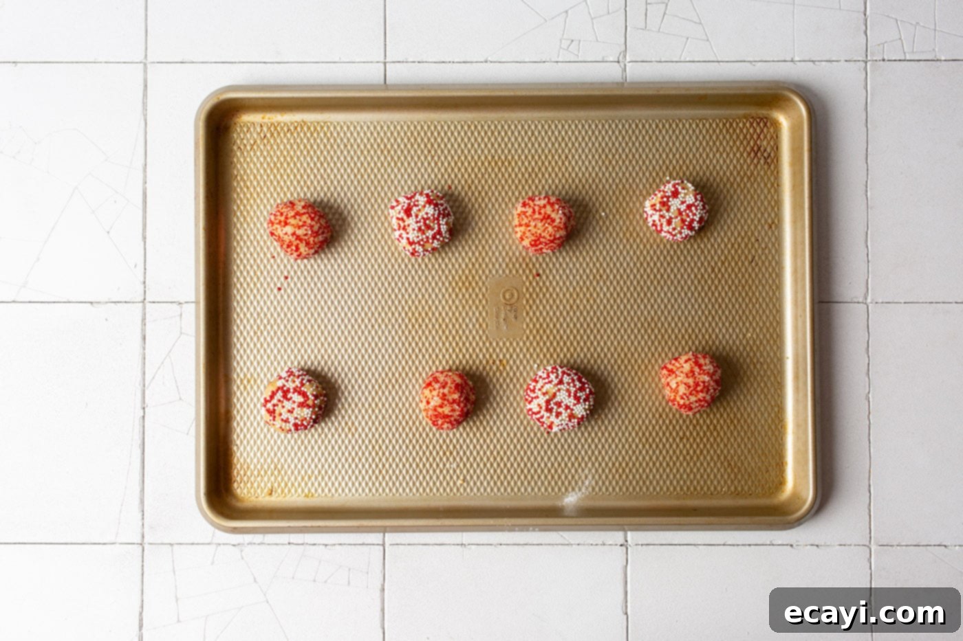 Sweet Christmas Kisses 8 peanut butter dough balls being rolled in a bowl of colorful Christmas sprinkles for a festive coating