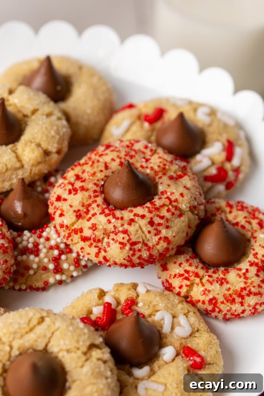 Sweet Christmas Kisses 9 close-up of festive Christmas Kiss Cookies on a white plate, highlighting the sprinkles and perfectly melted chocolate kiss