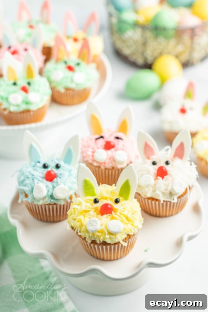 Boxed cake mix, canned frosting, flaked coconut, and fun decorations make these darling Easter Bunny Cupcakes an easy and impressive dessert for the holiday. Colorful Easter bunny cupcakes arranged on a display, each featuring gum ears, marshmallow paws, and jelly bean noses.