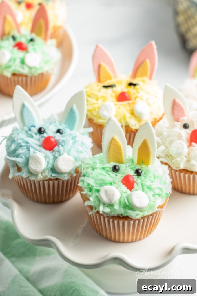 Boxed cake mix, canned frosting, flaked coconut, and fun decorations make these darling Easter Bunny Cupcake an easy and impressive dessert for the holiday. A close-up shot of a plate of cheerful bunny rabbit cupcakes, showcasing their vibrant colors and cute details.