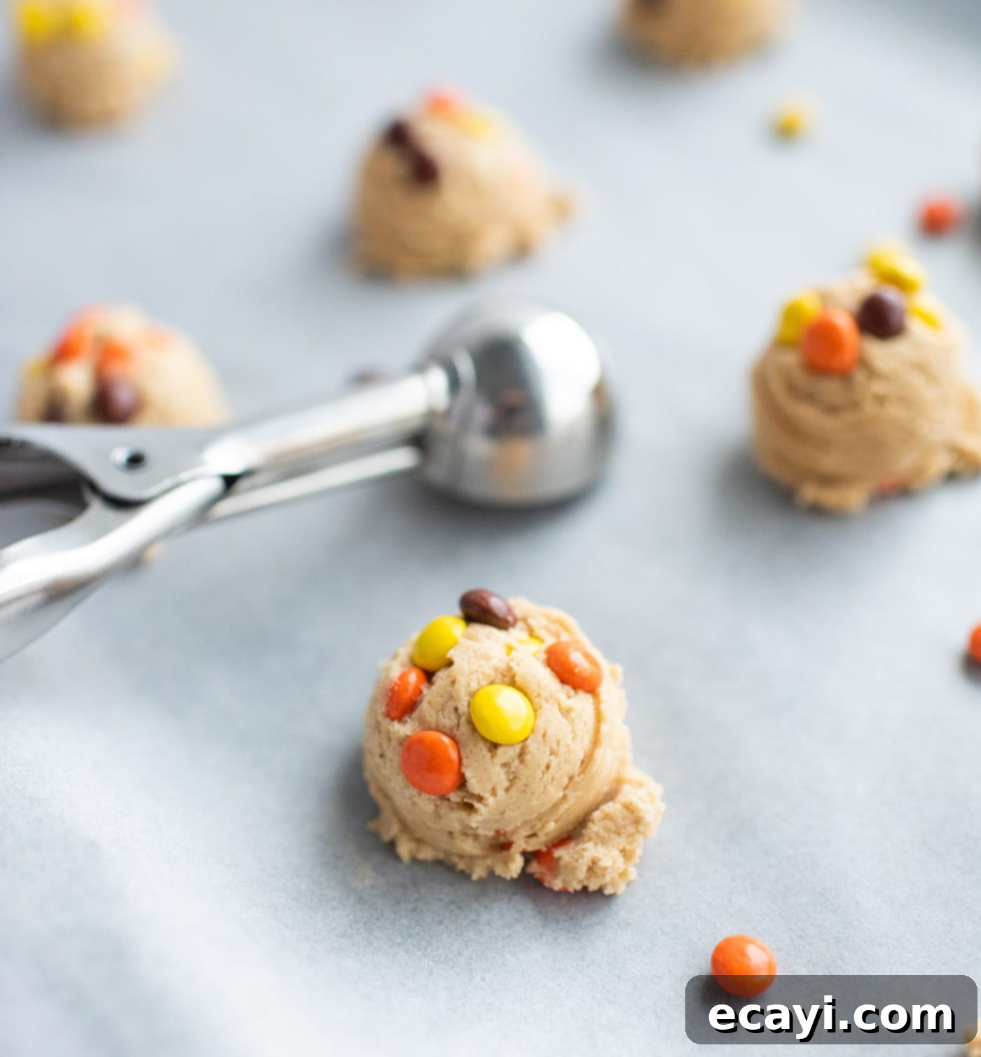 Ultimate Reese's Pieces Cookies 8 cookie scoop adding dough balls to parchment paper lined baking sheet