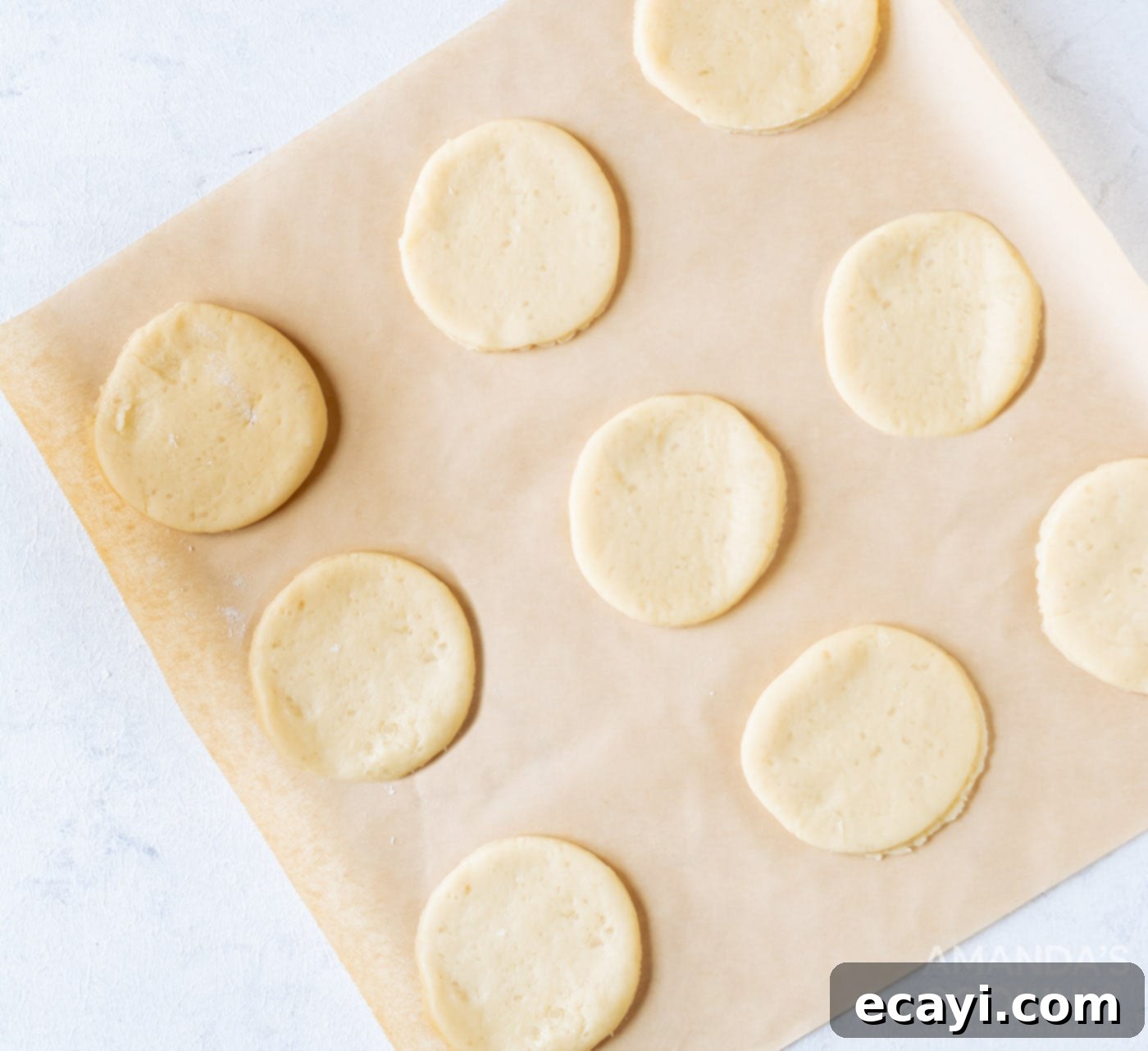 Soft Frosted Lofthouse Cookies 7 Cut out sugar cookies arranged on parchment paper on a baking sheet.