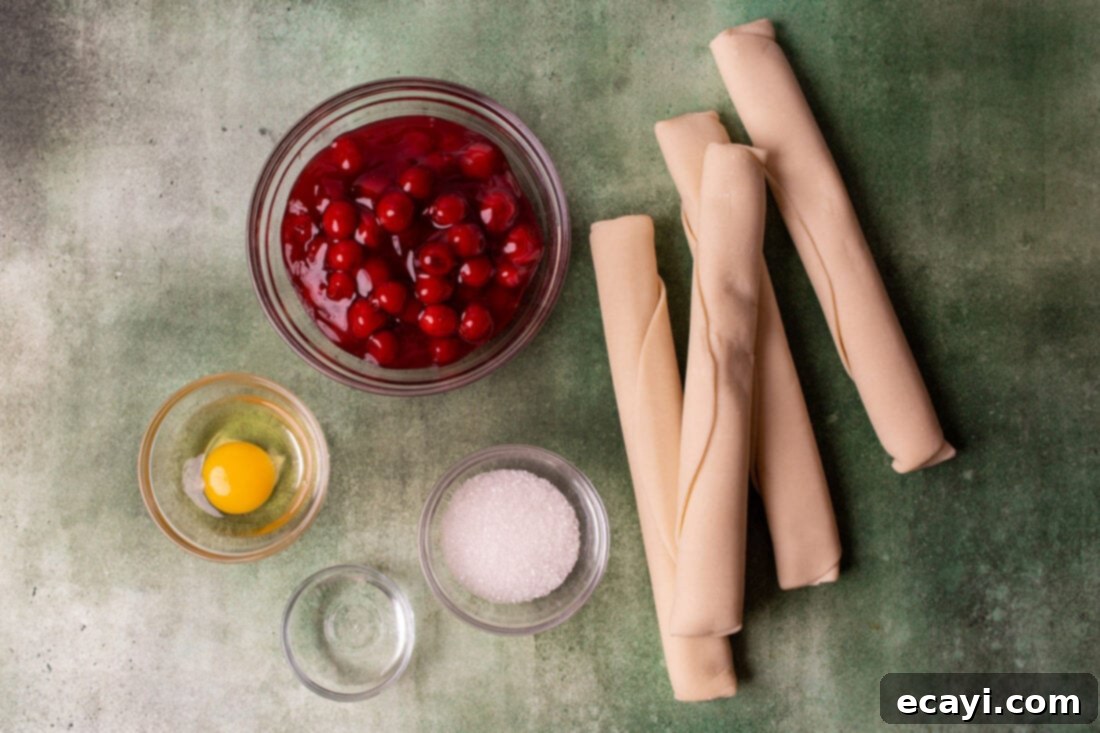 Cherry Pie Bites 4 Ingredients laid out for making cherry pie cookies, including pie dough, cherry pie filling, egg, and sugar.