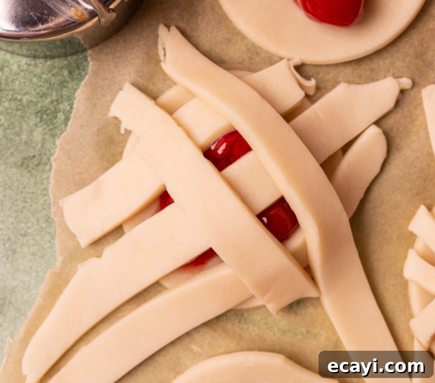 Cherry Pie Bites 6 Pie dough strips being woven into a lattice pattern over a cherry pie cookie