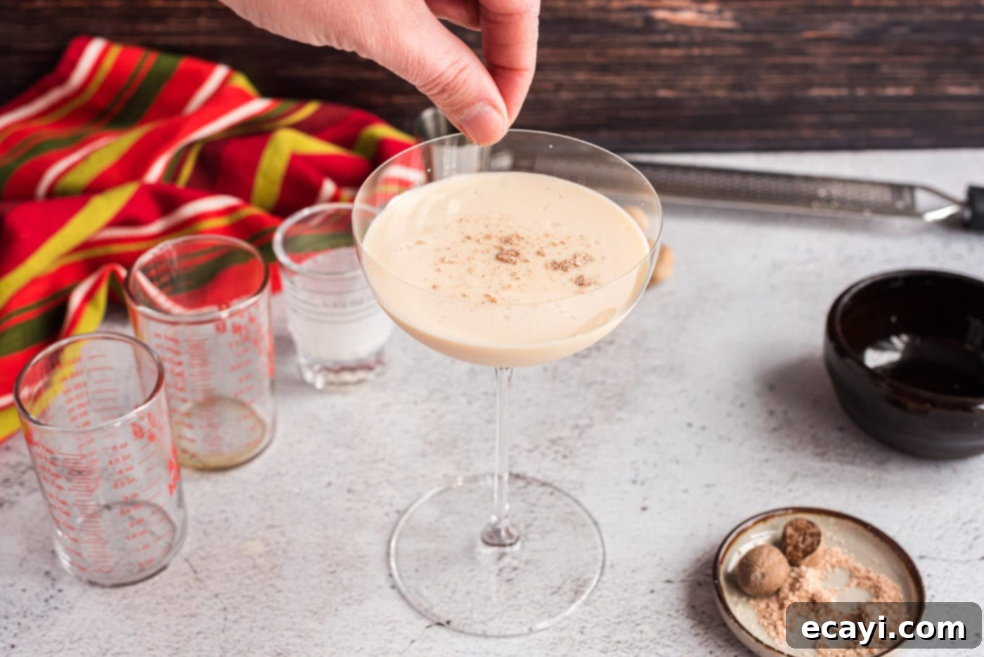 Velvet Cocoa Indulgence 9 A hand carefully sprinkling freshly ground nutmeg over the top of a Brandy Alexander cocktail.