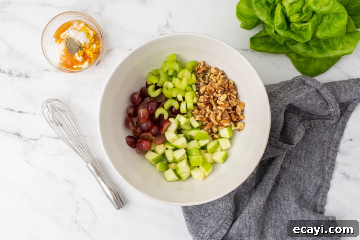 Crisp Apple Walnut Delight 5 Diced apples, sliced celery, halved grapes, and walnuts combined in a large mixing bowl, ready for dressing.