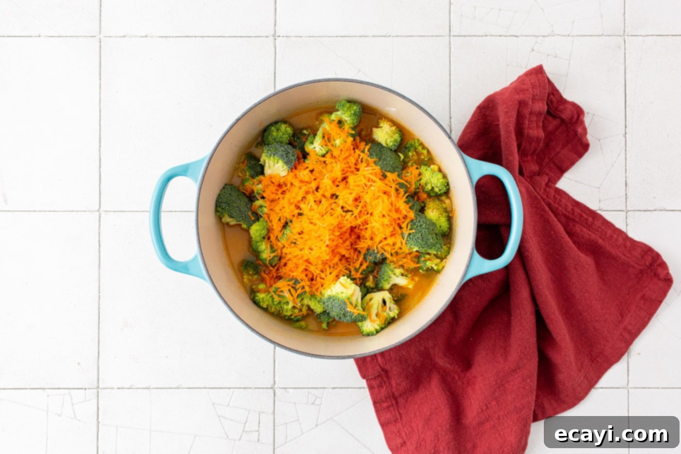 Golden Broccoli Cheddar Delight 6 Chopped broccoli florets and shredded carrots simmering in the flavorful broth in a dutch oven.