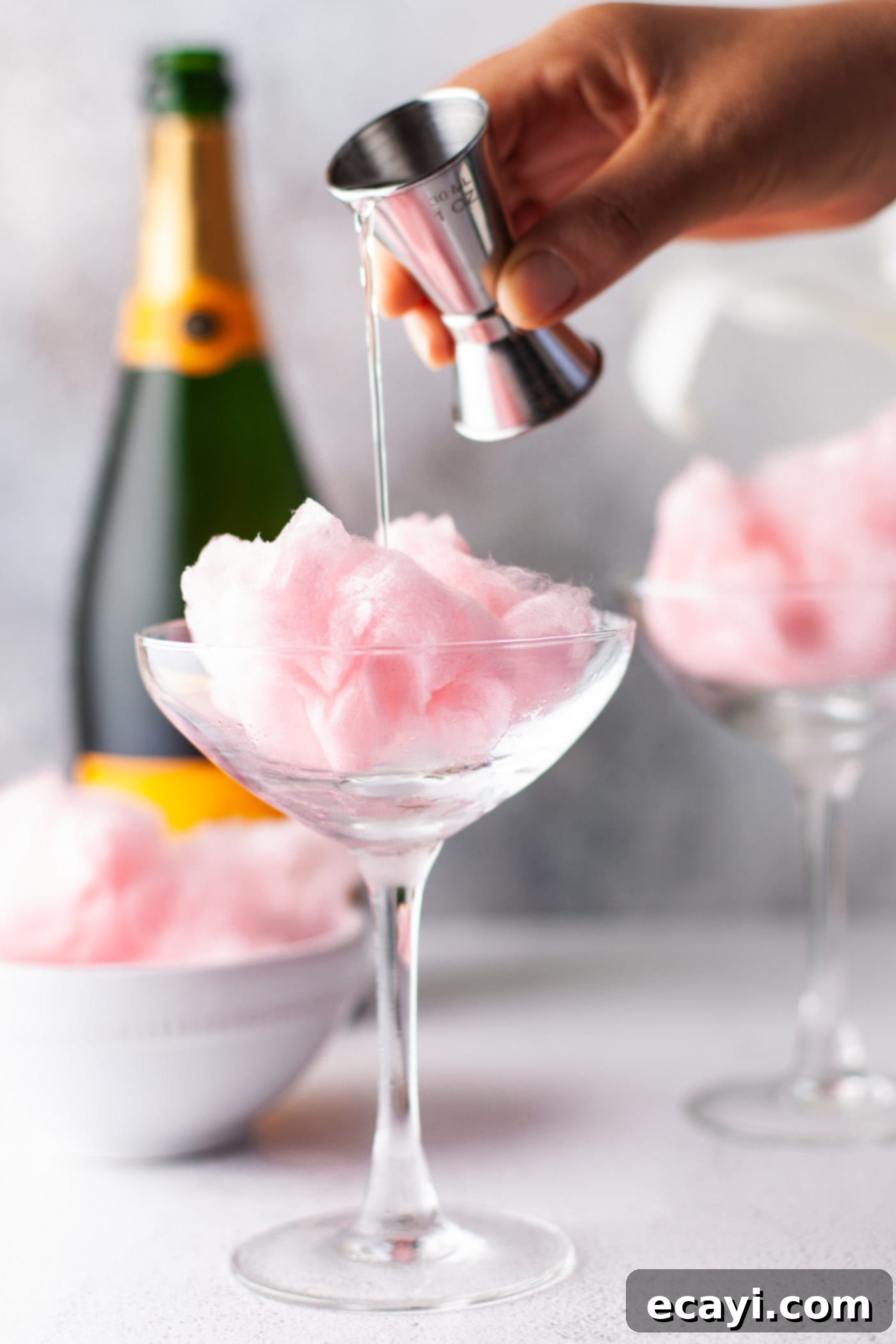 Whimsical Effervescence 4 hand pouring orange liquor into glass of cotton candy