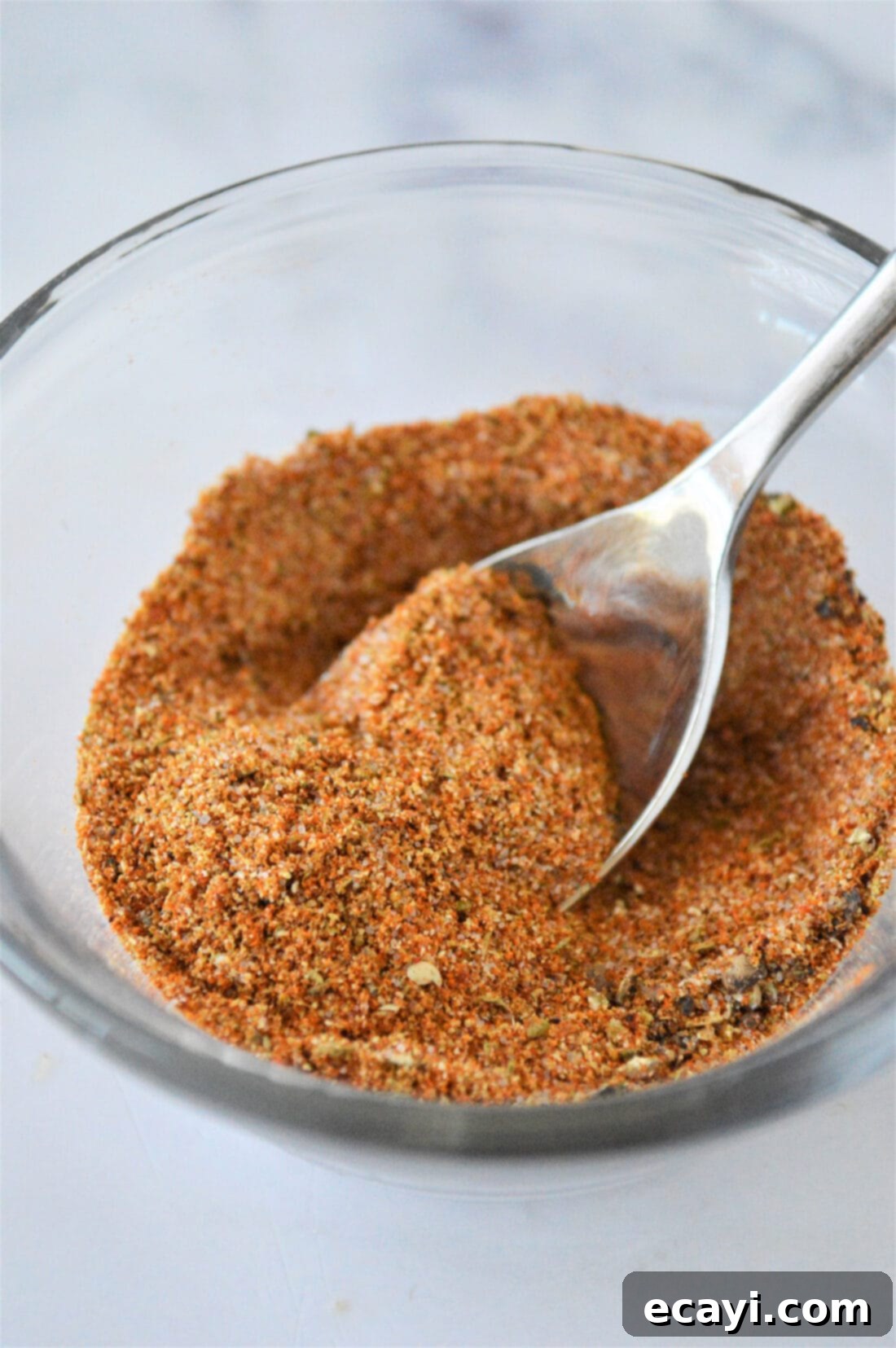 Golden Fry Seasoning 2 A bowl filled with vibrant homemade French fry seasoning, with a spoon resting inside, ready to elevate your dishes.