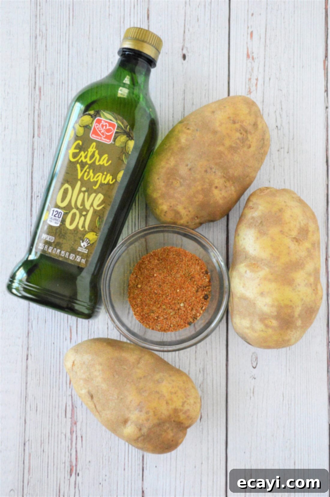 Oven Fries 4 A selection of fresh ingredients including Russet potatoes, olive oil, and a container of French fry seasoning, laid out on a wooden surface