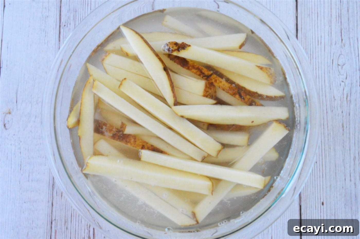 Oven Fries 5 Sliced potatoes soaking in a bowl of water to remove excess starch, a critical step for crispy fries