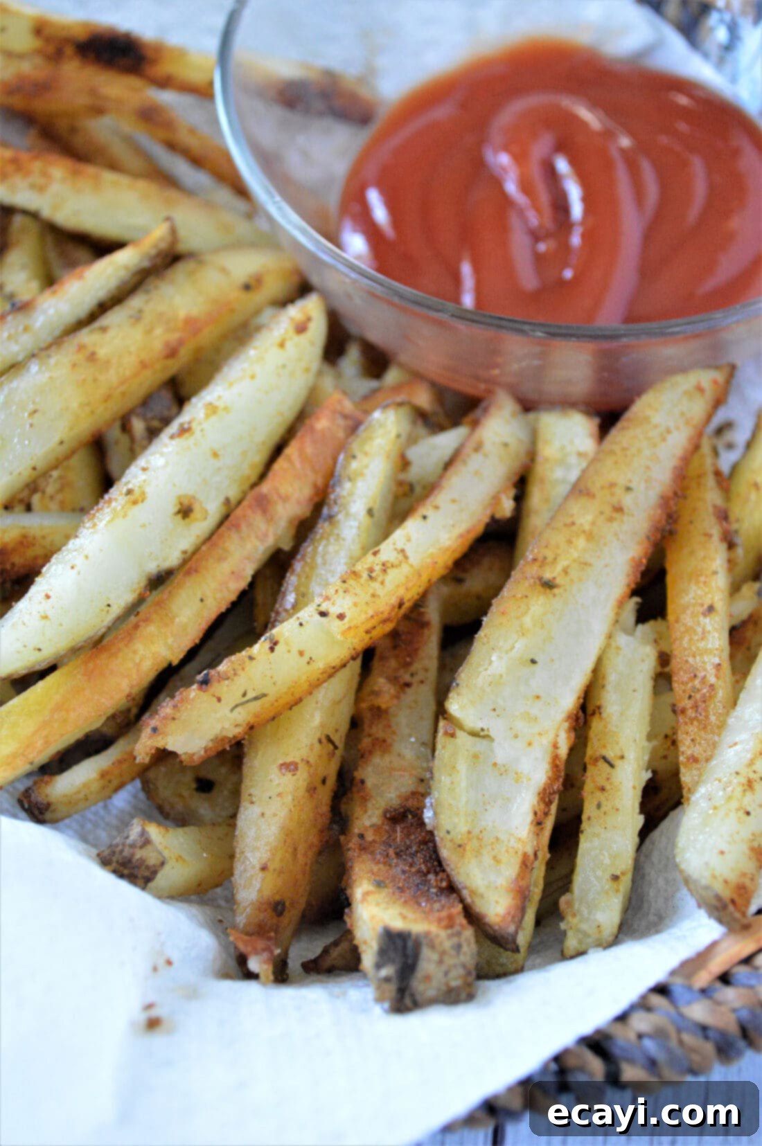 Oven Fries 7 A generous serving of golden, crispy baked French fries served in a fry basket, with a side of ketchup