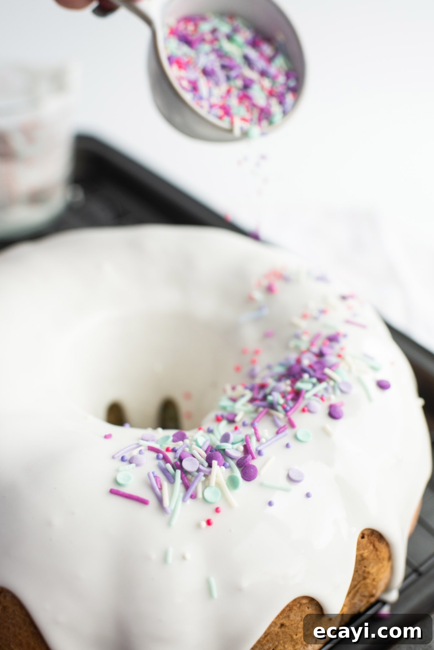 Enchanted Rainbow Bundt 12 Adding colorful sprinkles to the freshly glazed Unicorn Bundt Cake.
