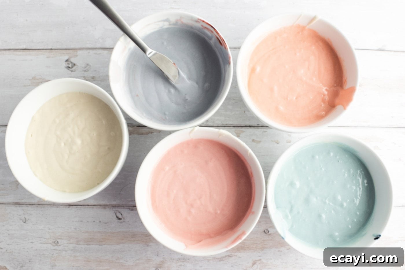 Enchanted Rainbow Bundt 7 Divided cake batter in bowls with various pastel food colorings.