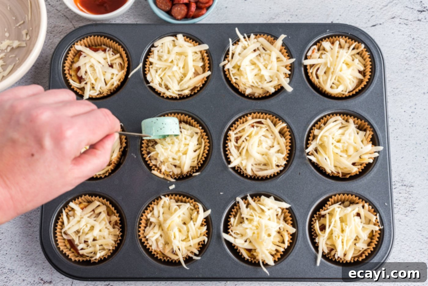 Cauliflower Crust Pizza Bites 8 adding cheese to cauliflower pizza bites in a muffin tin