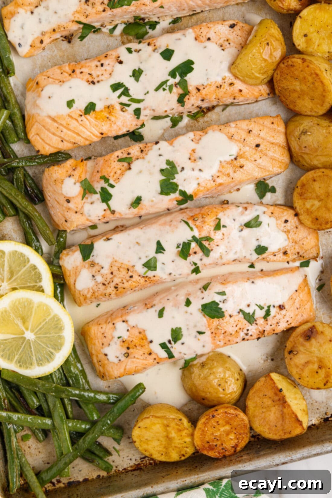 Oven Roasted Salmon Perfection 5 Close-up of baked salmon fillets with a generous serving of lemon cream sauce and fresh parsley