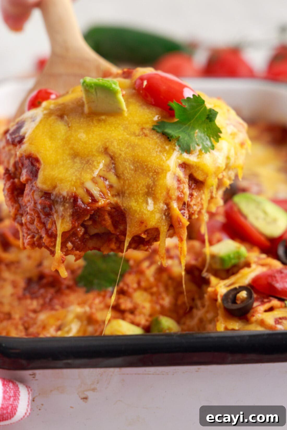 Cheesy Chicken Enchilada Bake 3 A spatula lifting a perfect serving of gooey Chicken Enchilada Casserole from a baking dish.
